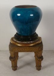 Vaso de porcelana forma globular esmalte turquesa, con pedestal de madera tallada y doara.