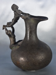 Jarra de bronce, asa con pareja acrobática. Alto: 18,5 cm.