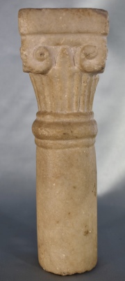 Fragmento de columna con capitel, de mármol tallado. Alto: 22 cm.