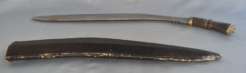 KUKRI, cuchillo, cabo de asta y bronce, hoja de acero. Vaina de cuero. Largo total: 72 cm.