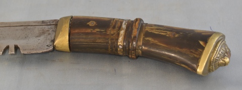 KUKRI, cuchillo, cabo de asta y bronce, hoja de acero. Vaina de cuero. Largo total: 72 cm.