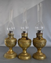 Tres lámparas Miller a querosene de bronce con fanales. Alto promedio: 54 cm. -3 B ó 38/3