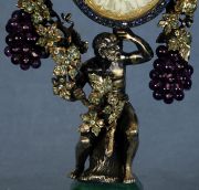Reloj de sobremesa antiguo con personaje y racimos de uvas, faltantes.