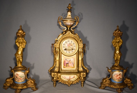 Garniture estilo L. XVI, porcelana de Sevres y bronce dorado, sin péndulo. Reloj con dos llaves y dos figuras de niños.