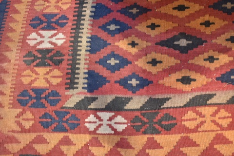 Carpeta Kilim de lana con motivos geométricos. 3 franjas en la guarda, azul, rojo y naranja. Mide 285 x 195. Desgastes