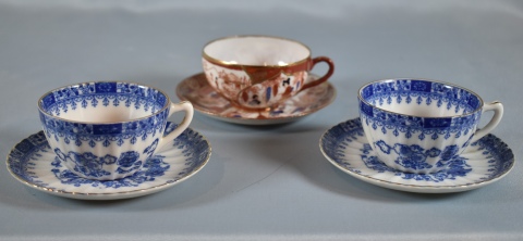 Tres tazas en porcelana japonesa, dos azules y una bordó.