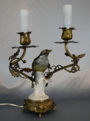 Velador con ave de porcelana y dos brazos de bronce.