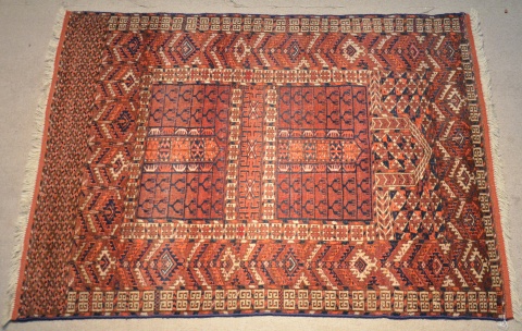 Alfombra turcomana de lana. Dos rectangulos y grandes guardas sobre fondo bordó. 140 x 111 cm