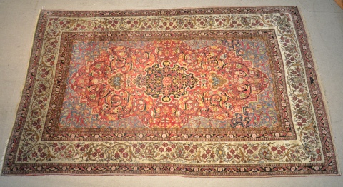 Alfombra persa de lana y seda, campo bordo y celeste con medallón negro y flores polícromas. 214 x 137 214 x 137cm