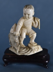 Niño con Pez, figura, de marfil tallada. Base madera, pata averiada.