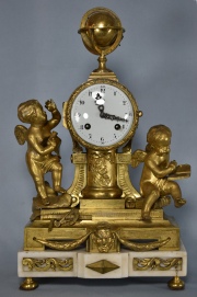Reloj francés de bronce dorado y mármol. Angelitos a los lados. Alto: 40 cm.