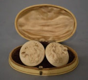 PAR DE GEMELOS DE MARFIL, con decoración de cabezas de león en relieve. En caja oval del mismo material. Largo caja: 10