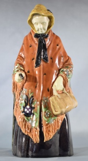 MUJER CON CARTERA Y BASTON, figura inglesa de cerámica policromada. Al dorso marca K.G. Alto: 25,5 cm.