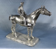 Jockey a caballo, escultura. plateada. riendas faltantes. Alto: 28 cm. Frente: 32 cm.