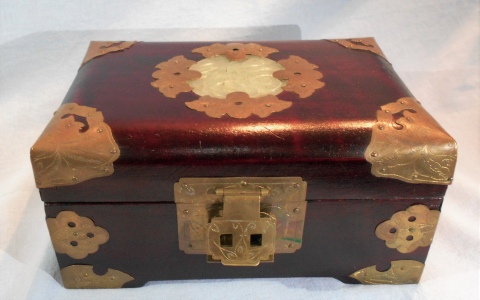 ALHAJERO CHINO, de madera con aplicaciones de bronce y piedra tallada en la tapa. Forro interior en fucsia y dorado. Co