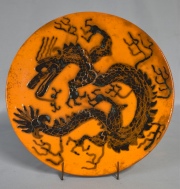 Plato cerámica naranja con dragones. Diám. 31 cm.