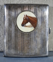 Cigarrera de alpaca con cabeza de caballo en esmalte. Mide: 8,8 x 7,5 cm.
