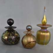 Tres perfumeros vidrio irisdicentene. Con tapones. Alto: 14, 10 y 8 cm.