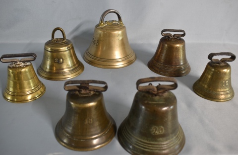 7 cencerros de bronce en forma de campana. Uno marca Ciervo. Alto máximo: 13 cm