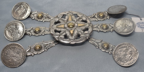 RASTRA PORTEÑA, realizada en plata con detalles de oro. Centro fundido calado con seis tiros y monedas a modo de botones