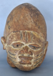 Máscara africana Gelede, Yoruba, en madera clara. De prominente frente, lleva incisiones en la frente y mejillas. 31 cm.