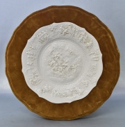 Plato en porcelana blanca, decoración en relieve. Diámetro: 23,5 cm.