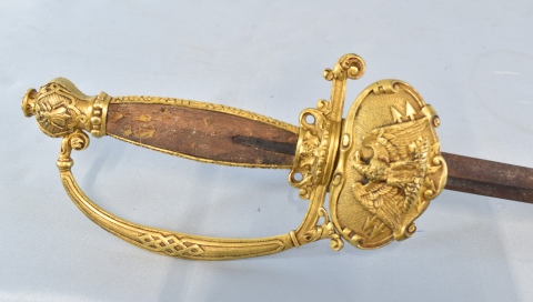 Espada de ceñir, empuñadura de bronce dorado con ornato de aguila. Hoja de tres planos. España, siglo XIX. Faltante.