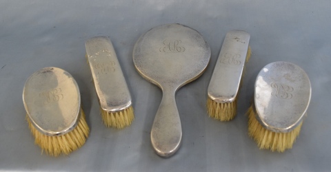 Cuatro cepillos y espejo de plata inglesa iniciales A.R. Abolladuras. 289-291