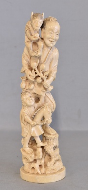 Hombre con mono y niño, talla de marfil. Fisura en la base. Alto: 25,5 cm.