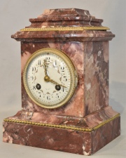 Reloj de mesa de mármol rosado y aplicaciones de bronce, mínimos desperfectos. Sin péndulo, con llave. Alto: 23 cm.  