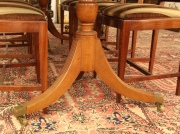 Mesa de comedor estilo Sheraton, de caoba. Regatones de bronce; con dos tablas de agregar.