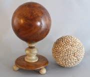 Esfera de madera sobre base, y esfera con caracoles. 2 piezas. Alto con base: 27 cm. Diámetro esfera: 14 cm.